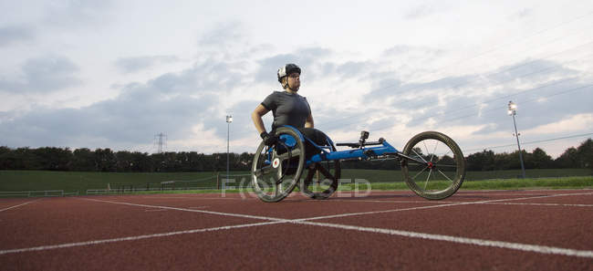 Determined young female paraplegic athlete training for wheelchair race on sports track — Stock Photo