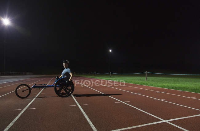 Portrait confident young female paraplegic athlete training for wheelchair race on sports track — Stock Photo