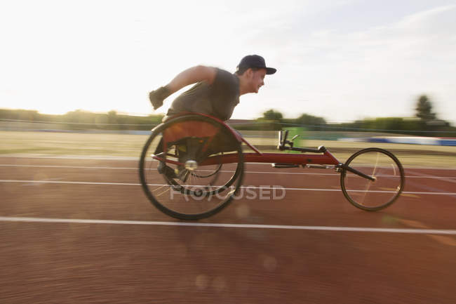 Athlète paraplégique adolescent excès de vitesse le long de la piste de sport dans la course en fauteuil roulant — Photo de stock