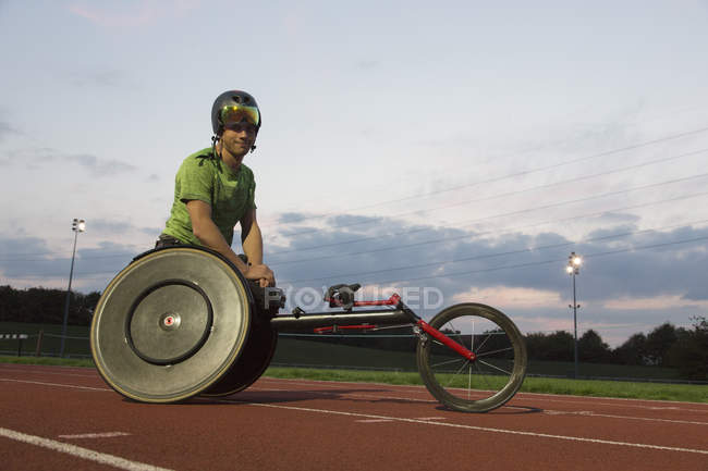 Portrait confident young male paraplegic athlete training for wheelchair race on sports track — Stock Photo