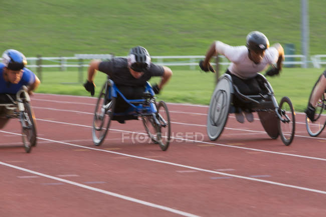 Determined paraplegic athlete speeding along sports track in wheelchair race — Stock Photo