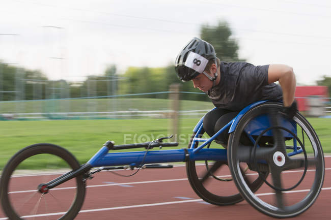 Determined young female paraplegic athlete speeding along sports track in wheelchair race — Stock Photo