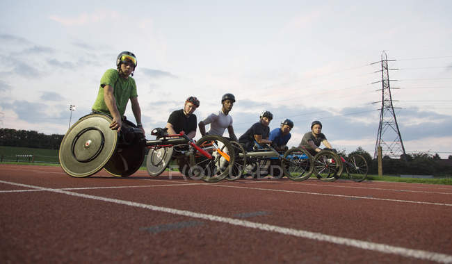 Retrato confiante, determinado treinamento de atletas paraplégicos para corrida em cadeira de rodas em pista de esportes — Fotografia de Stock