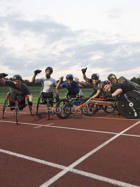 Portrait enthusiastic paraplegic athletes cheering, training for wheelchair race on sports track — Stock Photo