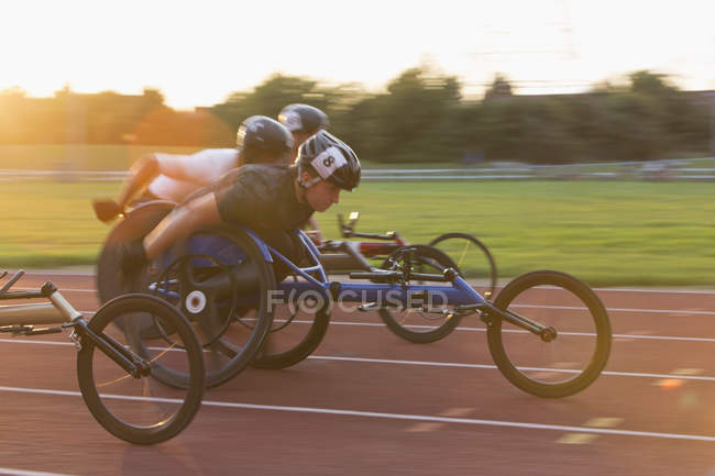 Atleti paraplegici che sfrecciano lungo la pista sportiva in gara su sedia a rotelle — Foto stock