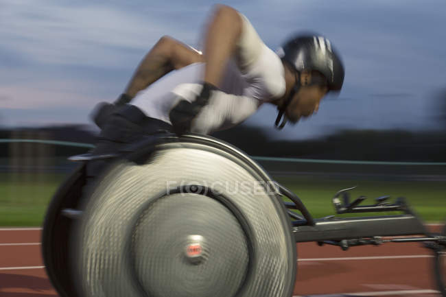 Atleta parapléjico exceso de velocidad a lo largo de pista deportiva en la carrera en silla de ruedas - foto de stock