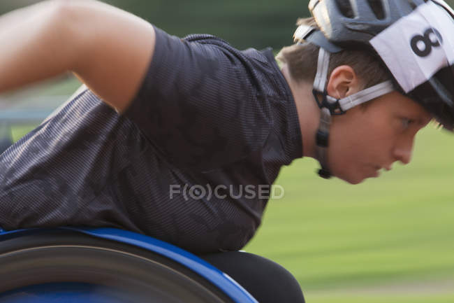 Atleta paraplegica determinata che corre lungo la pista sportiva durante la corsa in sedia a rotelle — Foto stock