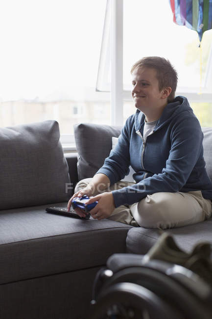 Smiling young woman playing video game on sofa — Stock Photo