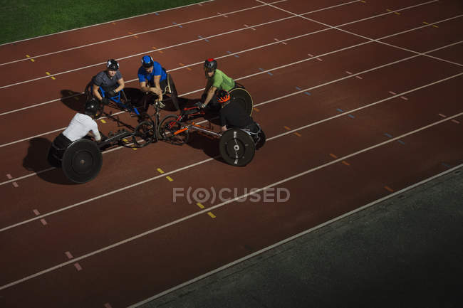 Паралитические спортсмены обнимаются на спортивной трассе, тренируются для гонки на инвалидных колясках — стоковое фото