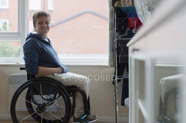Ritratto fiduciosa giovane donna seduta in sedia a rotelle alla finestra — Foto stock