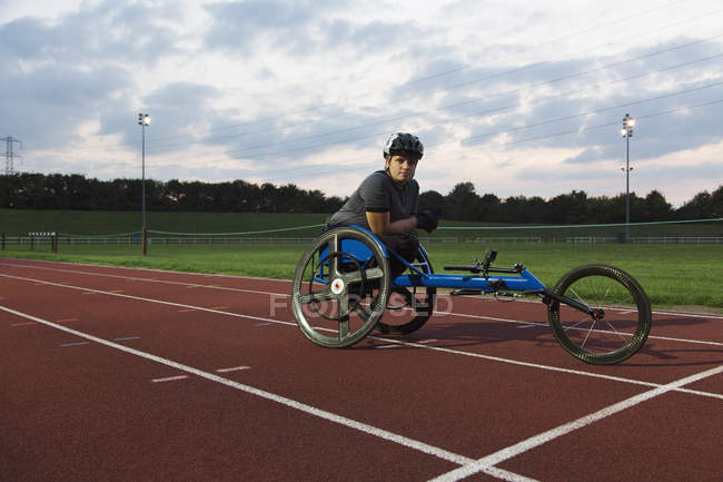Portrait athlète féminine paraplégique confiante s'entraînant pour la course en fauteuil roulant sur piste de sport — Photo de stock
