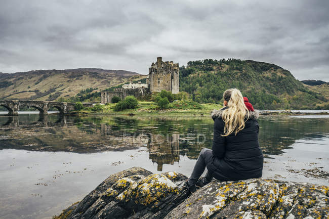 Жінка, насолоджуючись подання віддалений, waterfront замок, Шотландія — стокове фото