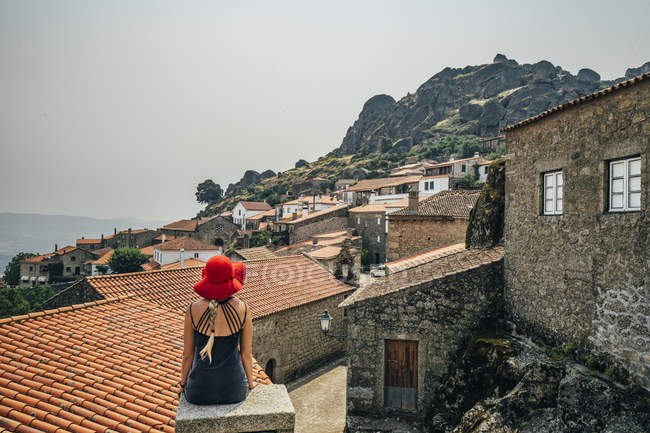 Жінка в червоних капелюх, дивлячись на будинки на схилі пагорба, Монсанто, Португалія — стокове фото