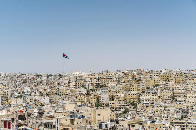 Йорданський прапор, що летить над Сонячний міської забудови, Амман, Йорданія — стокове фото