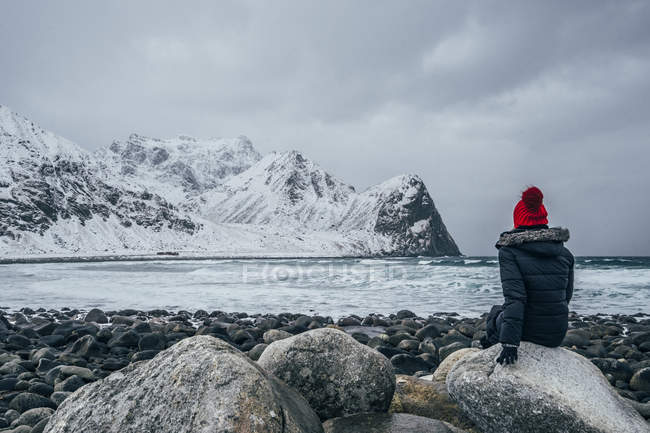 Frau in warmer Kleidung genießt einsamen, schneebedeckten Meer- und Bergblick, erhabene Inseln, Norwegen — Stockfoto