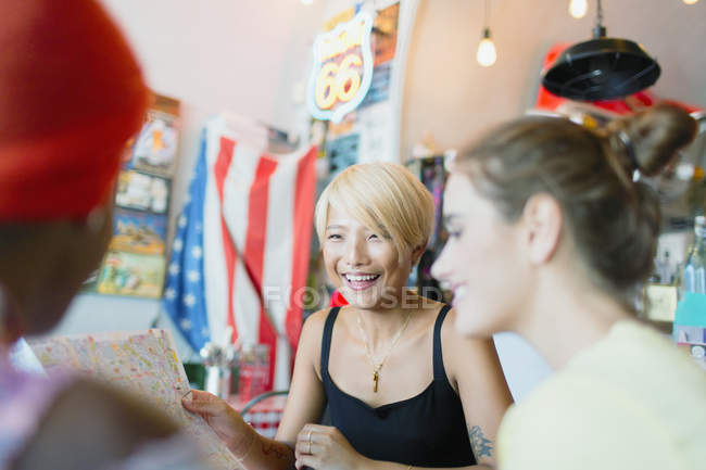Young women friends looking at map in restaurant — Stock Photo