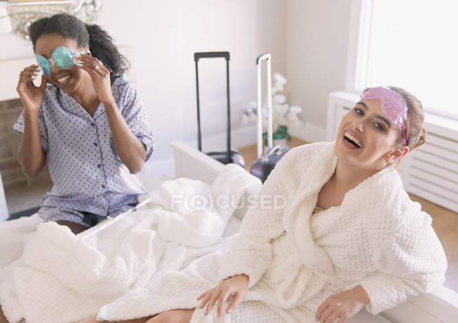 Ritratto felici giovani donne amiche che indossano maschere per gli occhi in camera da letto — Foto stock