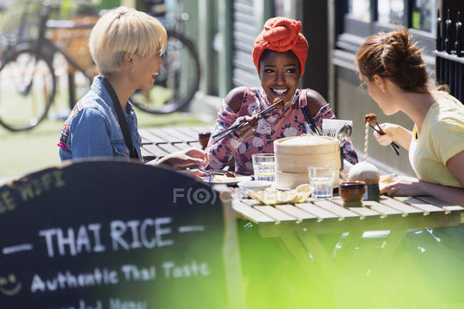 Молоді жінки друзі насолоджуються сніданком у сонячному тротуарному кафе — стокове фото