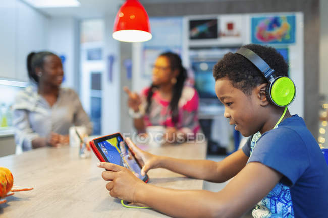 Boy with headphones and digital tablet playing video game — Stock Photo