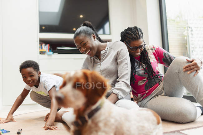 Mehrgenerationenfamilie spielt mit Hund im Wohnzimmer — Stockfoto