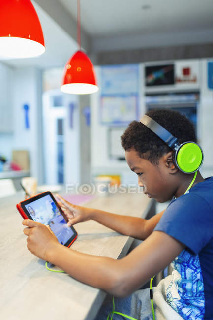 Menino com fones de ouvido e tablet digital jogando videogame — Fotografia de Stock