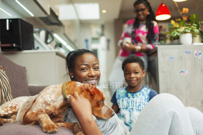 Retrato sonriente familia con perro en casa - foto de stock