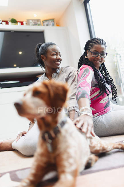 Mãe e filha adulta com cão no chão da sala de estar — Fotografia de Stock