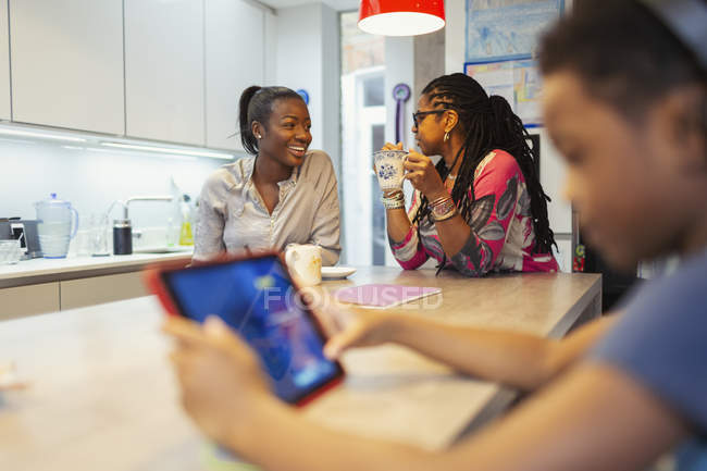 Mother and adult daughter talking in kitchen — Stock Photo