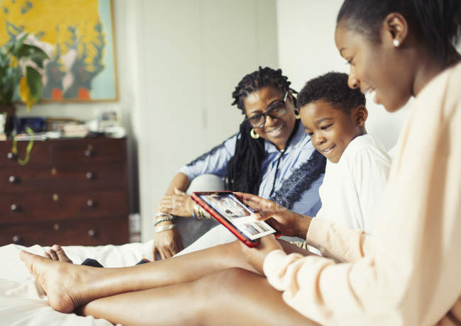 Multi-generation family using digital tablet on bed — Stock Photo