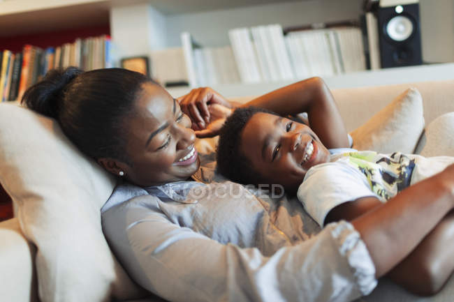 Retrato feliz, cariñosa madre e hijo abrazándose en el sofá de la sala de estar - foto de stock