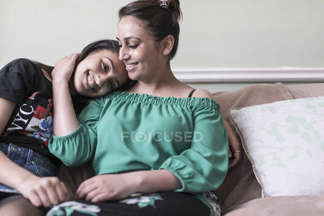 Ласковые мать и дочь обнимаются на диване в гостиной — стоковое фото