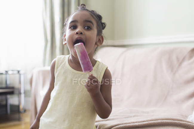 Cute toddler girl eating flavored ice — Stock Photo