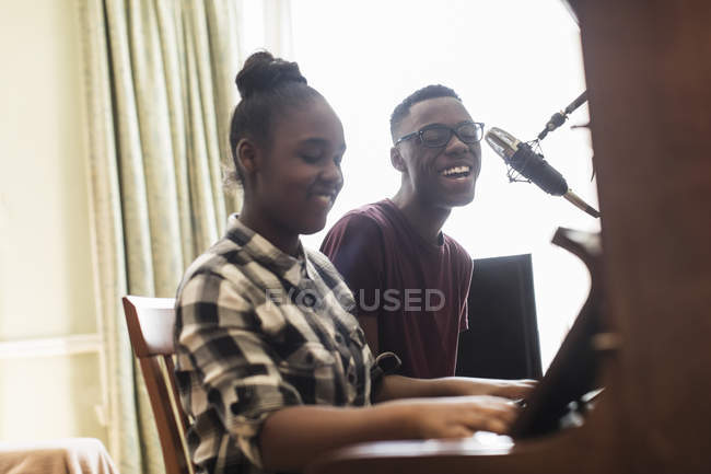 Adolescent frère et soeur jouer du piano et chanter — Photo de stock