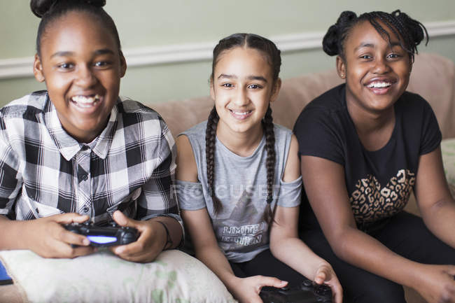 Portrait smiling tween girl friends playing video game on sofa — Stock Photo