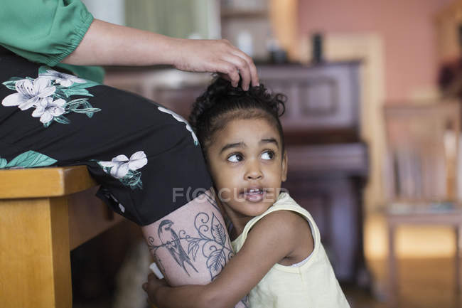 Cute toddler girl hugging mothers legs — Stock Photo
