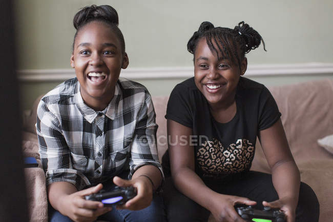 Tween girl friends playing video game on living room sofa — Stock Photo