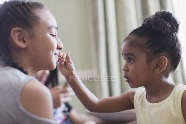 Linda niña aplicando brillo de labios a los labios de la hermana - foto de stock