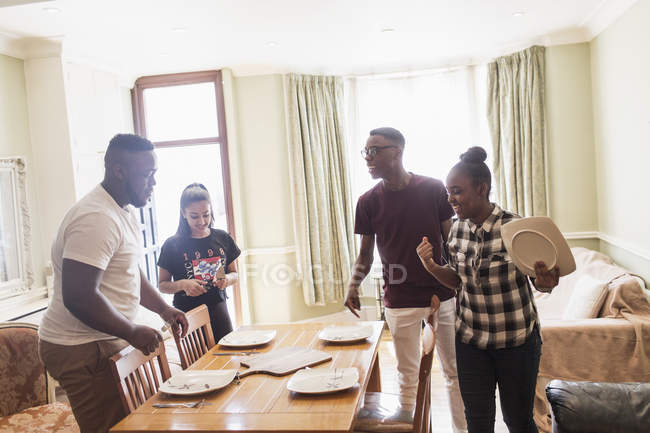 Подростковые братья и сёстры устанавливают обеденный стол — стоковое фото