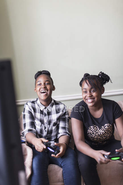 Feliz chica amigos jugando videojuego en la sala de estar - foto de stock