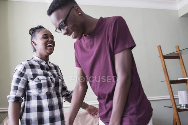Счастливые брат и сестра смеются в гостиной — стоковое фото