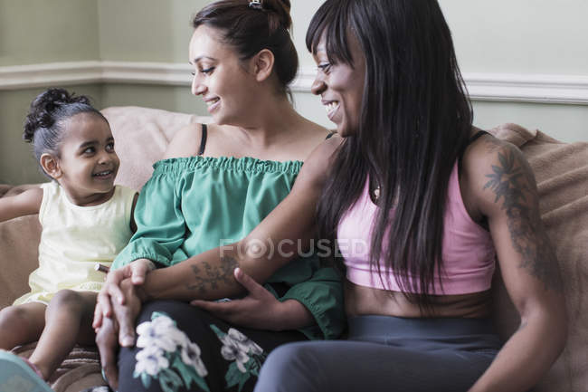 Ласкава пара з лесбійською дочкою на дивані у вітальні — стокове фото