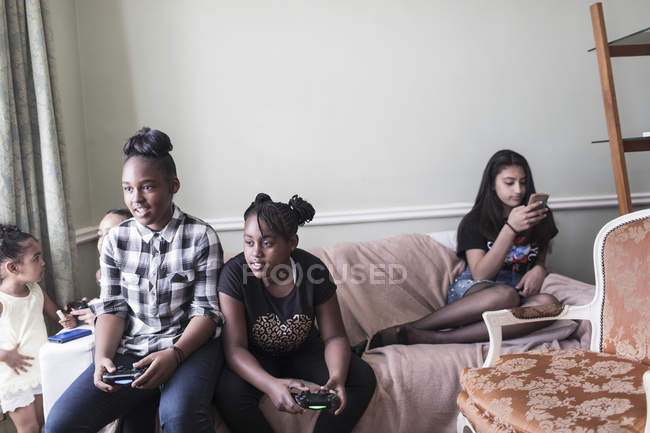 Між дівчатами друзі грають у відеоігри на дивані у вітальні — стокове фото