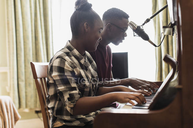 Teenage brother and sister playing piano — Stock Photo