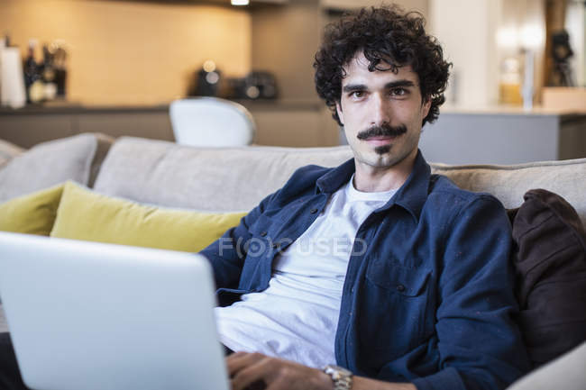 Ritratto uomo sicuro di sé utilizzando il computer portatile sul divano del soggiorno — Foto stock