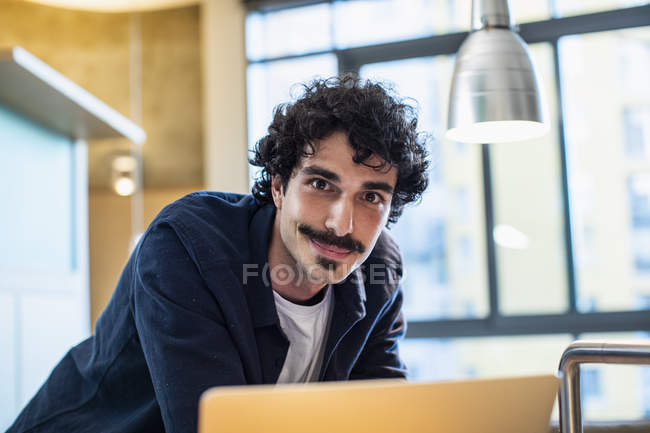 Портрет улыбающийся человек с помощью ноутбука дома — стоковое фото