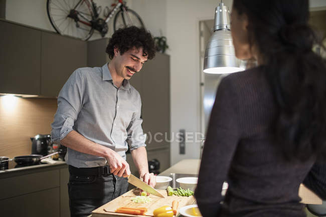 Pareja cortar verduras, cocinar la cena en la cocina del apartamento - foto de stock