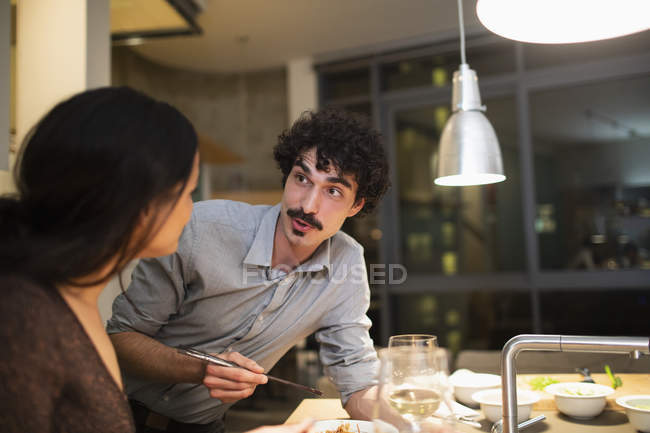 Couple eating dinner with chopsticks in apartment kitchen — Stock Photo