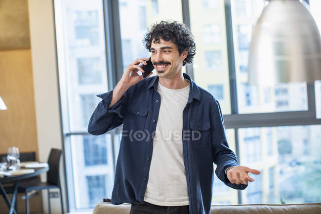 Hombre hablando por teléfono inteligente en el apartamento - foto de stock