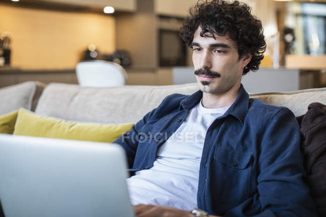 Людина використовує ноутбук на дивані — стокове фото