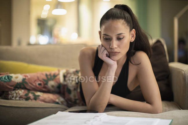 Donna concentrata in pigiama leggere documenti sul divano del soggiorno — Foto stock